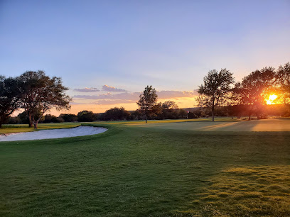 A lush golf course green and sand bunker at Delaware Springs, photographed at sunset with bright light shining through the trees.
